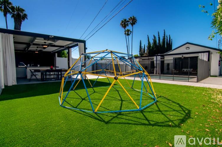 A large blue and yellow playground structure sits in the middle of a green lawn.