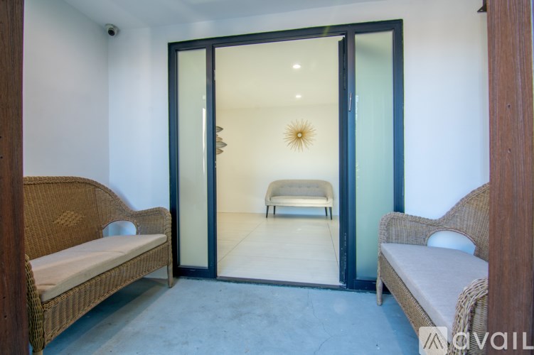 A living room with a sofa, a chair, and a glass door leading to a bedroom.