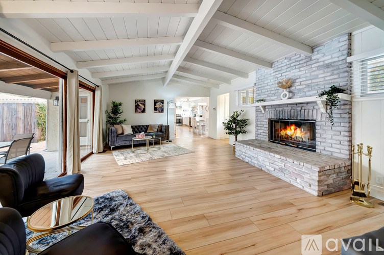 A living room with a stone fireplace and wooden floors.
