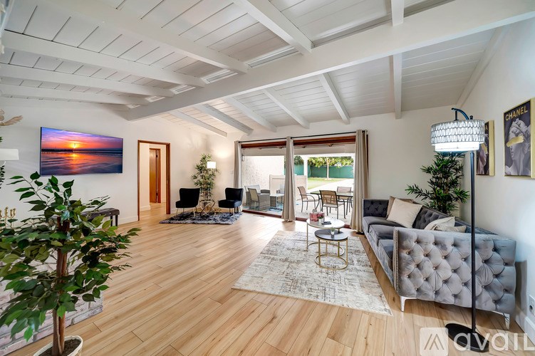 A living room with a grey sofa, a coffee table, a TV, and a painting of a sunset on the wall.