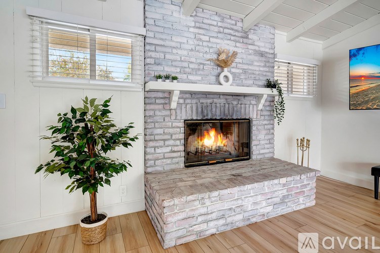A living room with a fireplace and a potted plant.