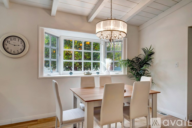 A dining room with a table and chairs and a window.