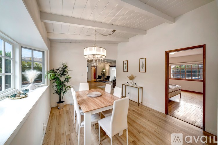 A dining room with a wooden table and white chairs.