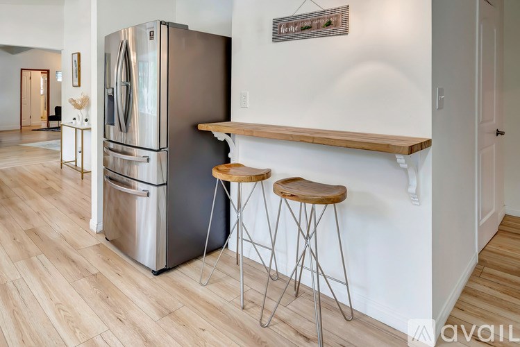 A kitchen with a stainless steel refrigerator and two bar stools.