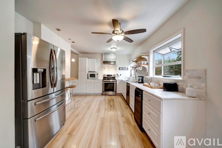 A modern kitchen with wooden floors and stainless steel appliances.