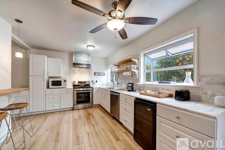 A kitchen with a wood floor and white cabinets.
