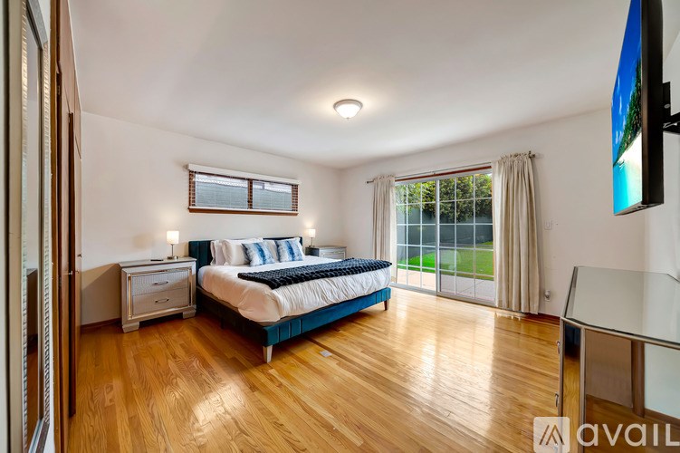 A bedroom with a bed, nightstand, and a window with curtains.