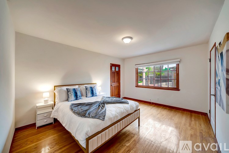 A bedroom with a bed, nightstand, and window.