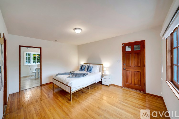 A bedroom with a bed, nightstand, and a window with a view of a balcony.