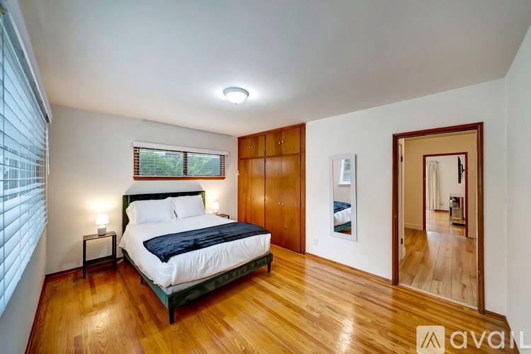 A bedroom with a bed, nightstand, and a window with blinds.