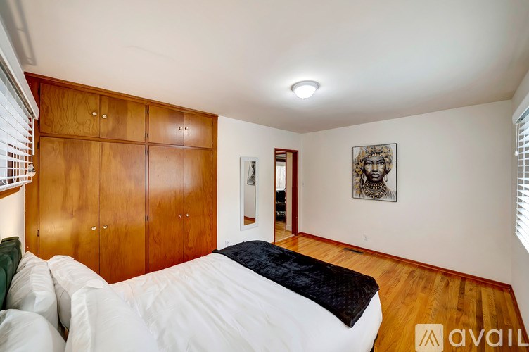 A bedroom with a bed, wooden wardrobe, and a picture on the wall.