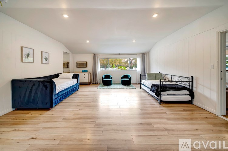 A bedroom with a large bed and a blue ottoman.