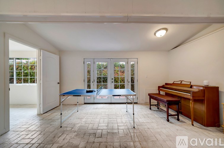 A room with a table and chairs and a piano.