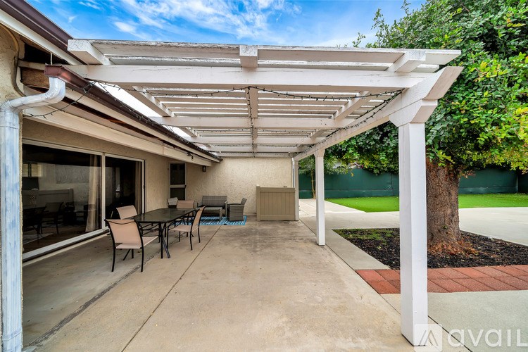 A patio with a table and chairs under a white pergola.