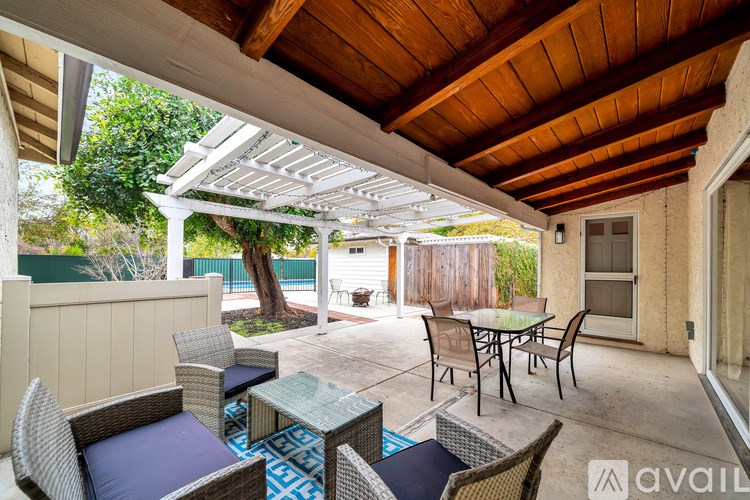 A patio with a table and chairs under a roof.