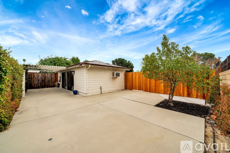 A house with a brown fence and a tree in front.