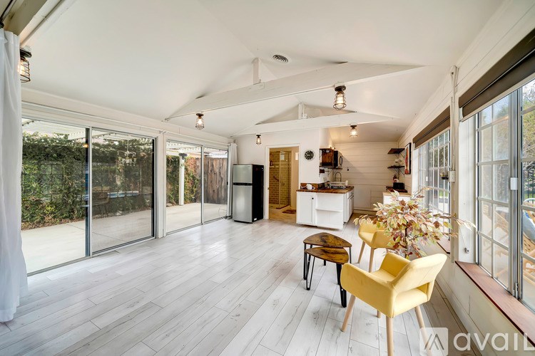 A living room with a yellow chair and a dining table.
