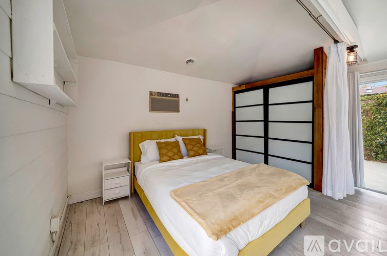 A bedroom with a large bed and a sliding door leading to a balcony.