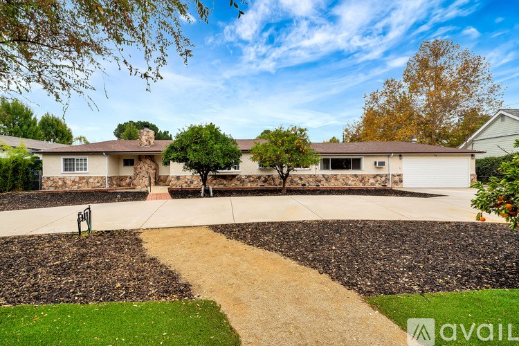A house with a stone wall and a tree in front of it.