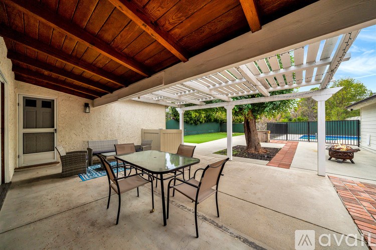 A patio with a table and chairs under a pergola.