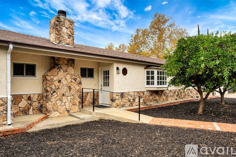 A house with a stone chimney and a tree in front.