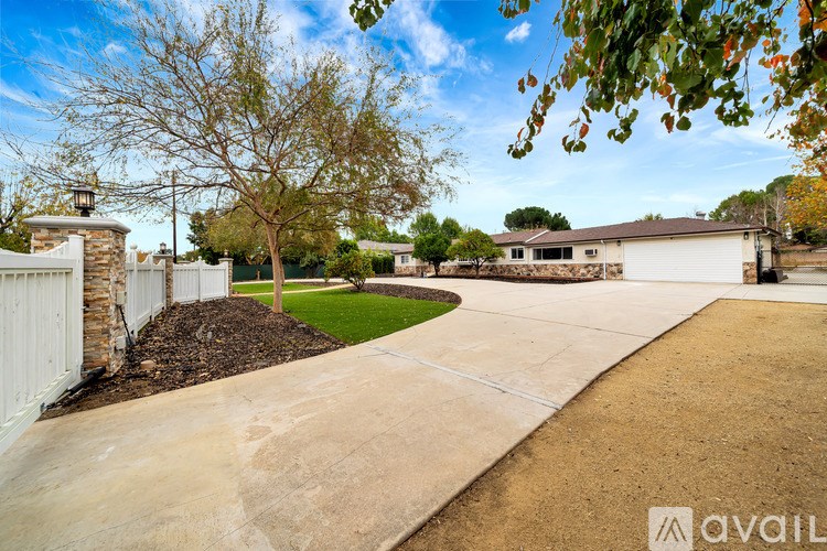 A house with a driveway and a tree in front of it.