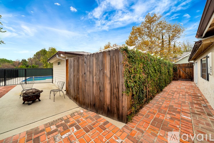 A backyard with a wooden fence and a brick pathway.