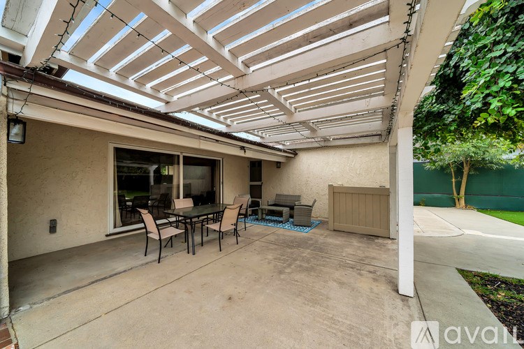 A patio with a table and chairs under a white pergola.