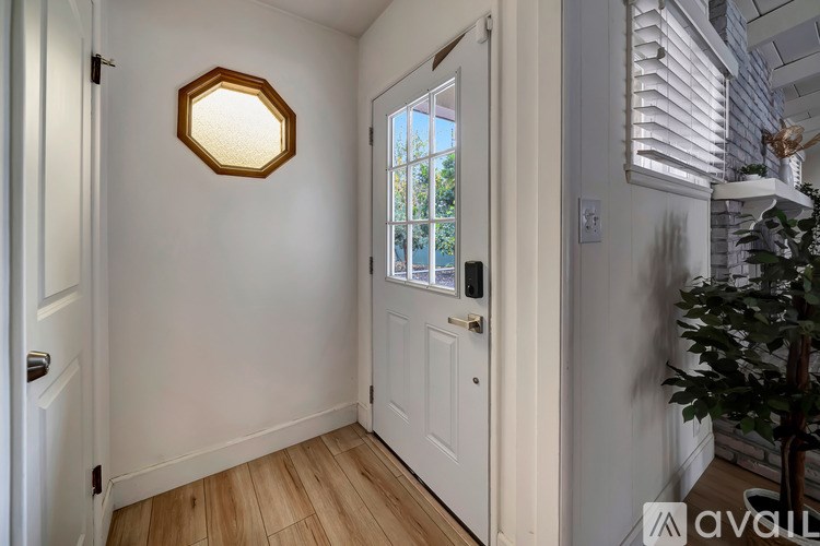 A white door with a window and a plant on the side.