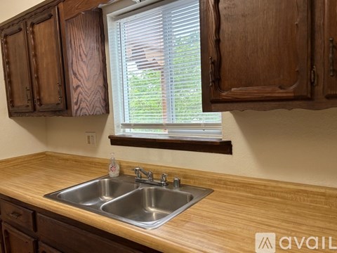 A kitchen with wooden cabinets and a window above the sink.