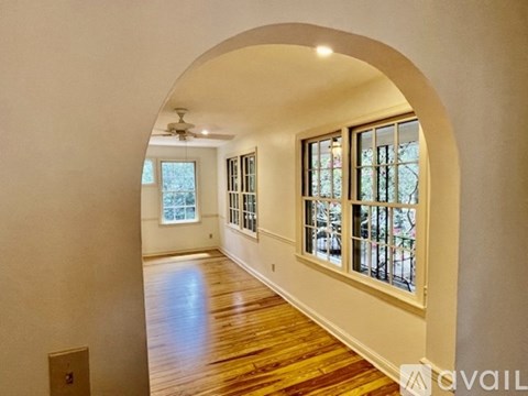 A spacious room with a wooden floor and a large arched doorway leading to another room.