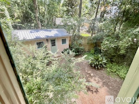 A small house with a green door is surrounded by greenery.