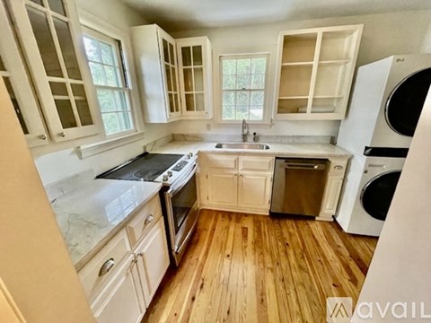 A kitchen with wooden floors and white cabinets.