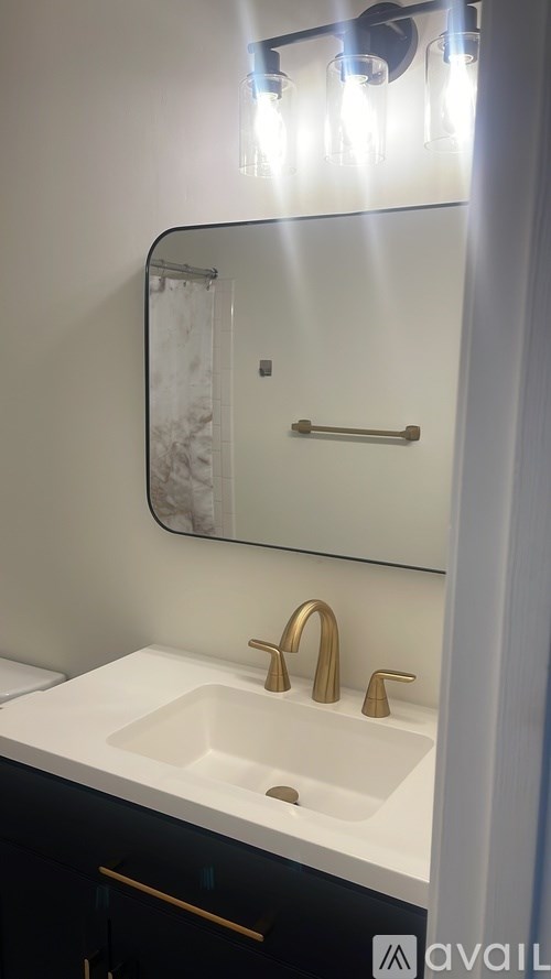 A bathroom sink with a gold faucet and a mirror above it.
