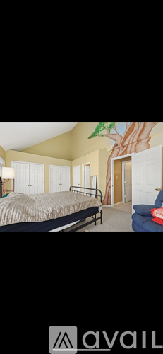 A bedroom with a bed, a chair, and a painting on the wall.