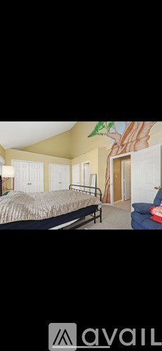 A bedroom with a bed, a chair, and a painting on the wall.