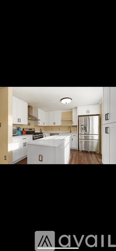 A modern kitchen with white cabinets and a wooden floor.