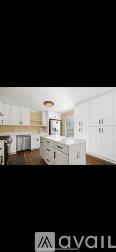 A kitchen with white cabinets and a wooden floor.