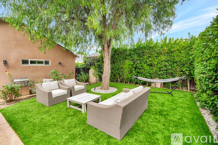 A backyard with a tree, a hammock, and a patio set.