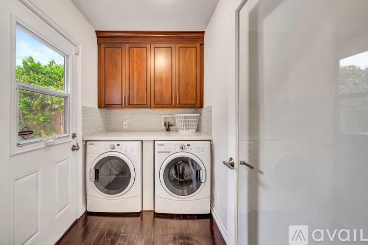 A laundry room with two washing machines and wooden cabinets.
