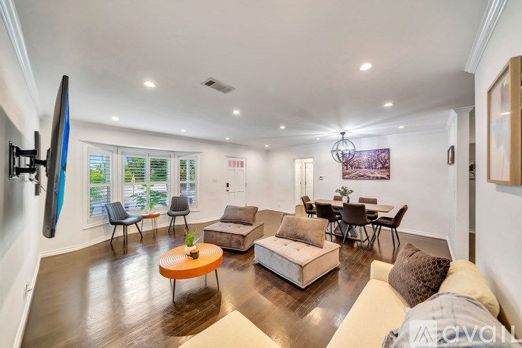 A living room with a white couch and a television on the wall.