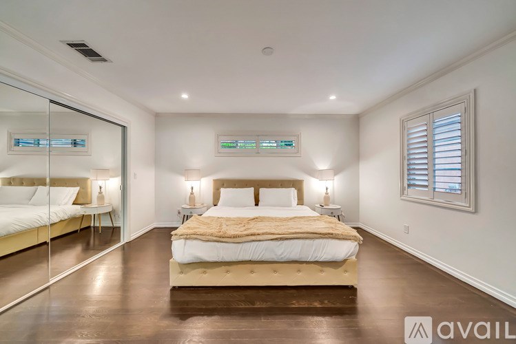 A bedroom with a large bed and a mirror on the wall.