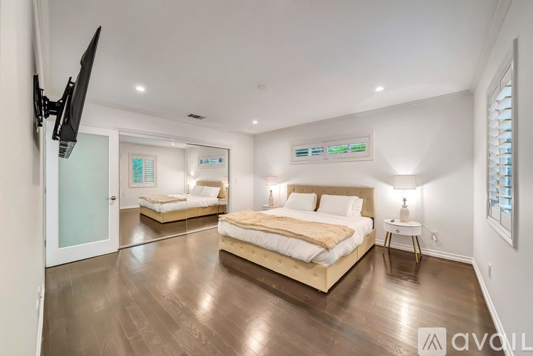 A bedroom with a large bed and a flat screen TV mounted on the wall.