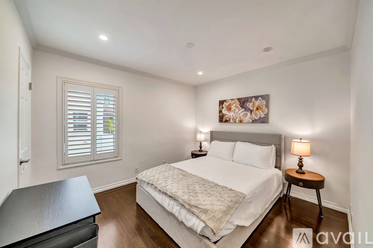 A bedroom with a bed, nightstand, and window with shutters.