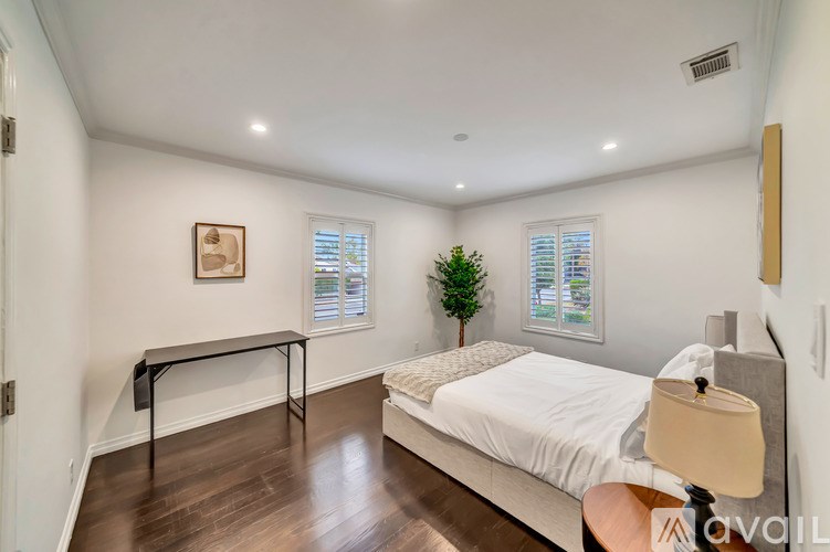 A bedroom with a bed, a small table, and a plant.