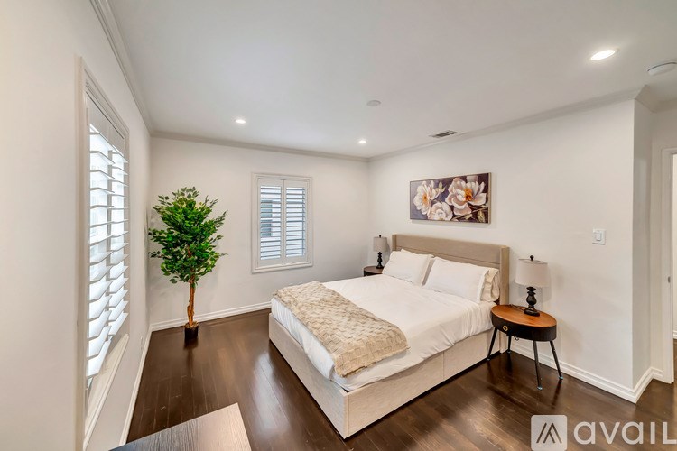 A bedroom with a bed, a small table, and a plant.
