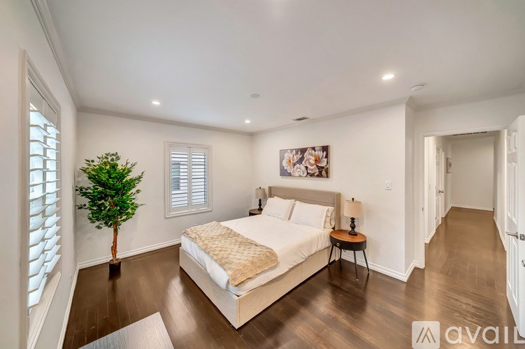 A bedroom with a large bed and a small tree.