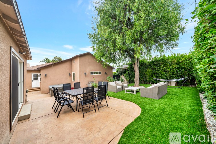 A patio with a table and chairs is surrounded by a garden.