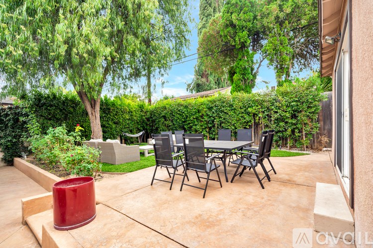 A patio with a table and chairs surrounded by greenery.