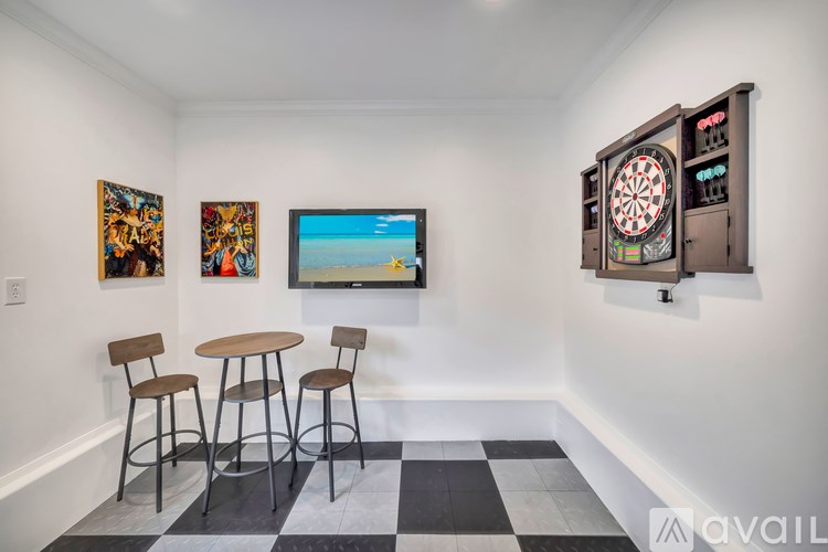 A room with a dartboard mounted on the wall and a painting of a beach scene on the wall.